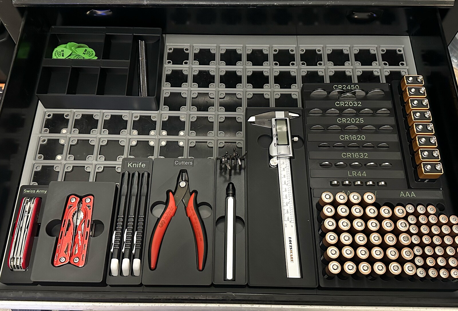 A tool chest drawer fully organized with Gridbox Pro prints: shadowbox trays for cutters and a multitool, labeled battery organizers, and a caliper tray